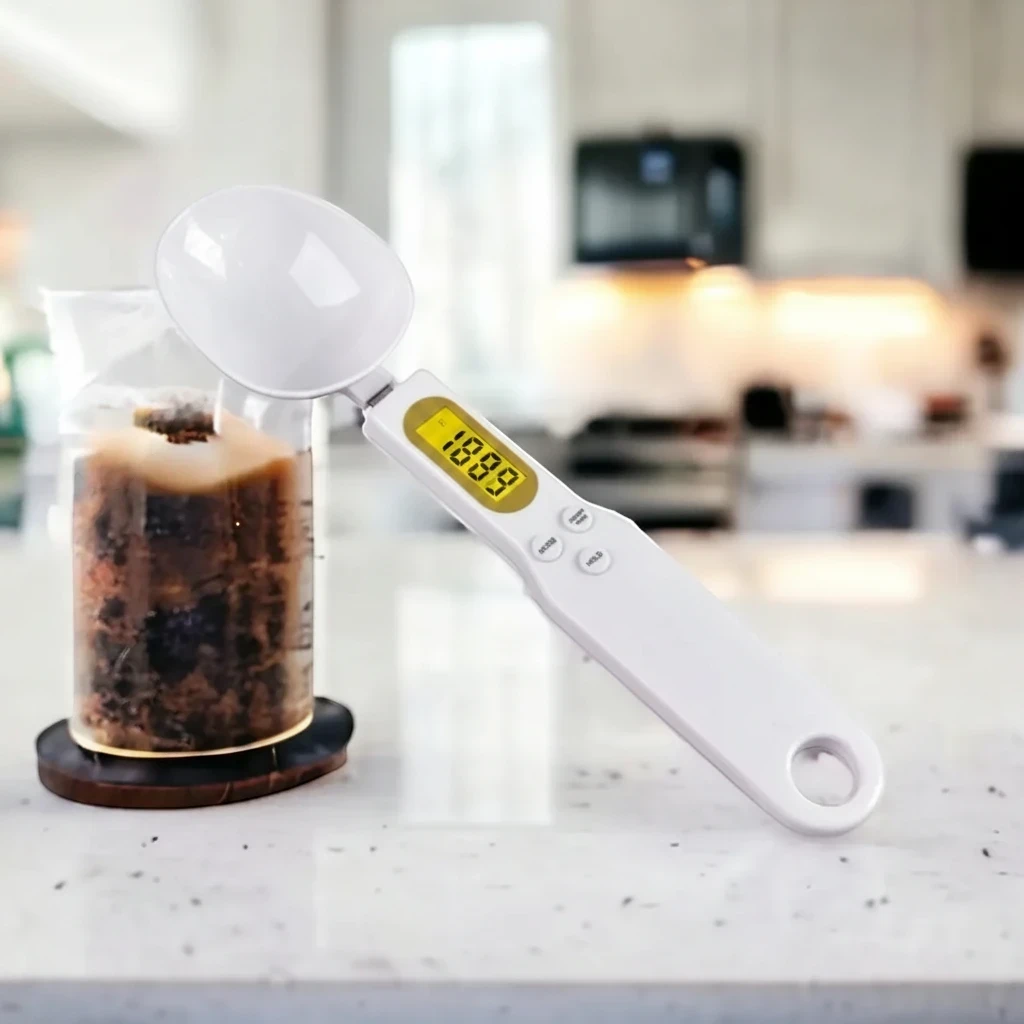 Colher medidora digital Decoricasa branca com visor LCD para pesagem precisa de ingredientes em cozinha moderna.