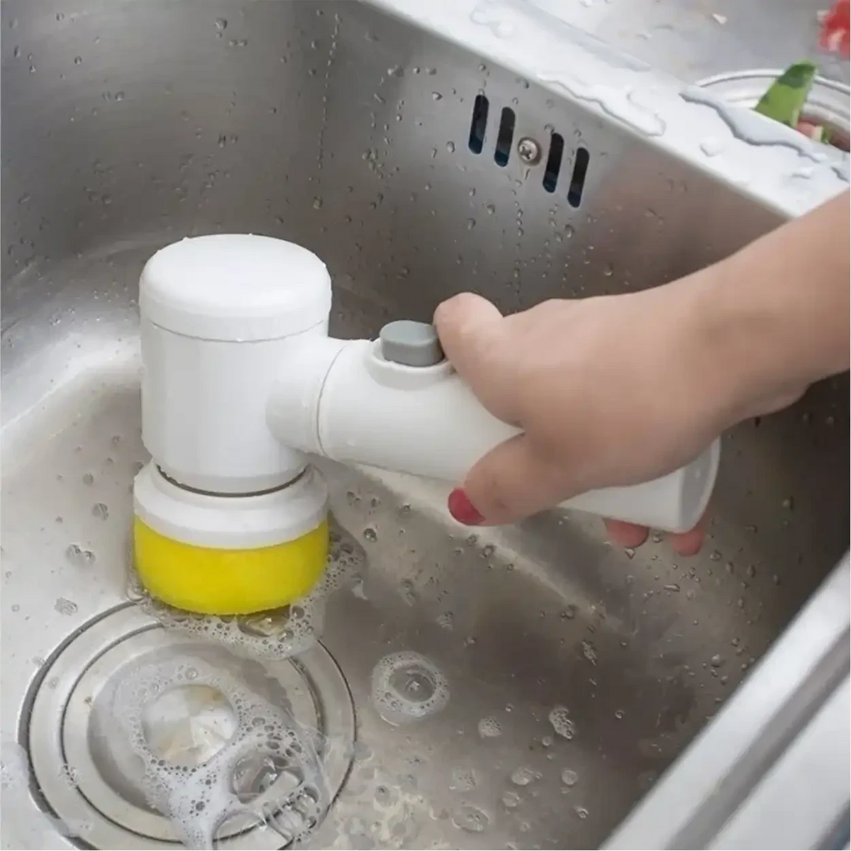 Escova elétrica de limpeza Decoricasa branca com cabeça amarela sendo usada para lavar pia de inox