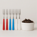 Kit de garfinhos coloridos Decoricasa com cabos vermelho, azul e branco ao lado de uma molheira com cubos de chocolate
