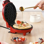 Máquina de waffle vermelha compacta Decoricasa com waffle fresco sendo coberto por mel e frutas em uma bancada