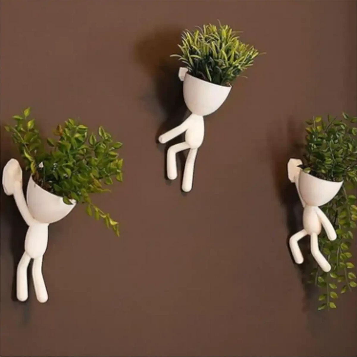 Kit com 3 mini vasos Decoricasa em formato de alpinistas brancos com plantas artificiais fixados em parede marrom