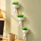 Kit com 3 mini vasos Decoricasa em formato de alpinistas brancos com plantas artificiais verdes fixados na parede