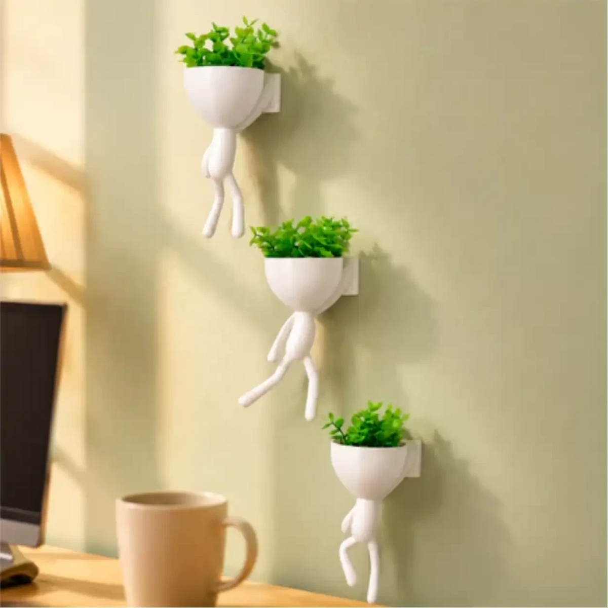 Kit com 3 mini vasos Decoricasa em formato de alpinistas brancos com plantas artificiais verdes fixados na parede