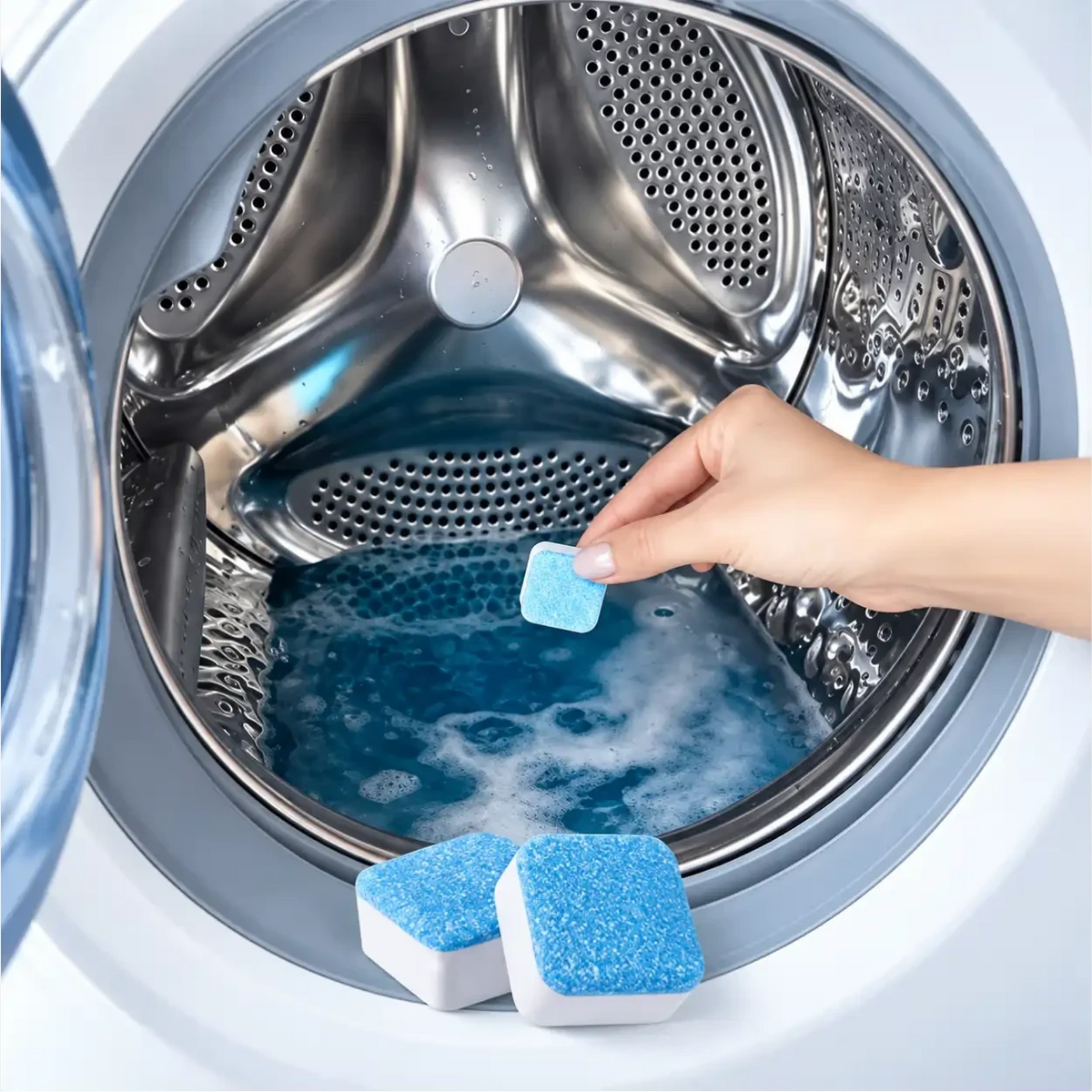 Mão colocando pastilha efervescente azul Puralav da Decoricasa no tambor da máquina de lavar para limpeza profunda