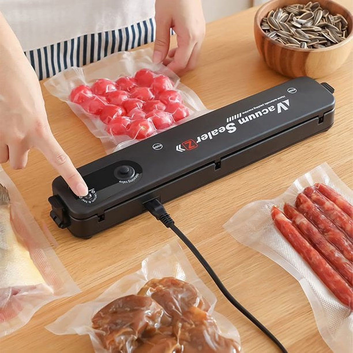 Seladora a vácuo Decoricasa preta compacta sendo usada para embalar alimentos em sacos plásticos sobre mesa de madeira
