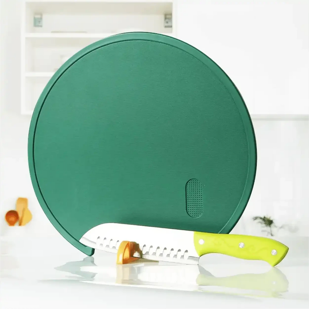 Tábua de corte redonda verde Decoricasa com suporte em pé e faca de cozinha sobre bancada branca
